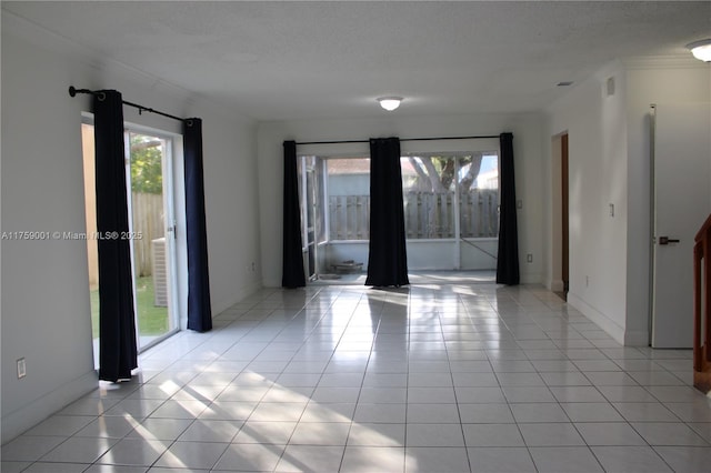 spare room with light tile patterned floors, baseboards, and a textured ceiling
