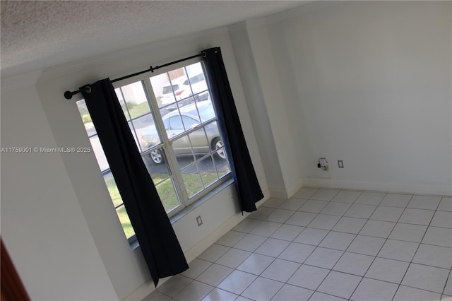 unfurnished room featuring light tile patterned flooring, a textured ceiling, and baseboards