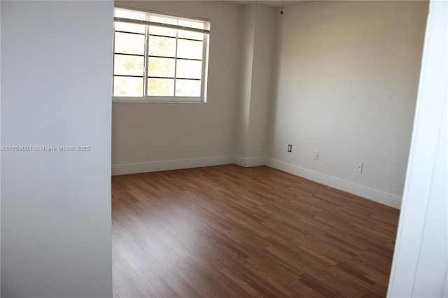 spare room with baseboards and wood finished floors