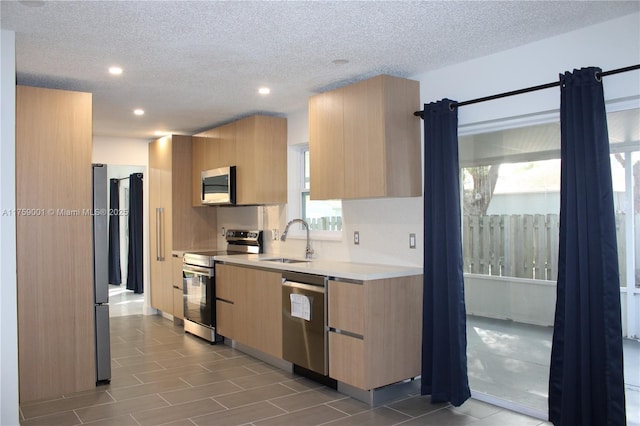 kitchen featuring light brown cabinetry, appliances with stainless steel finishes, modern cabinets, and a sink