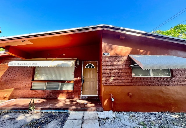 view of exterior entry featuring brick siding