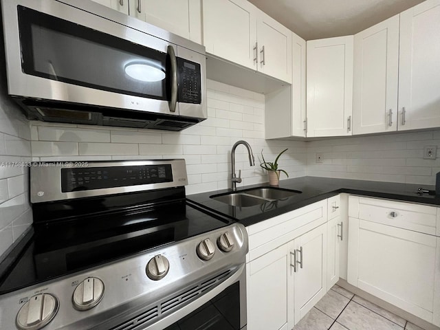 kitchen featuring tasteful backsplash, white cabinets, stainless steel appliances, and a sink