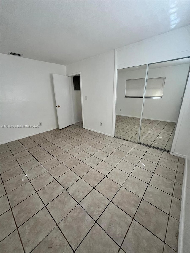 unfurnished bedroom with light tile patterned floors, a closet, and visible vents