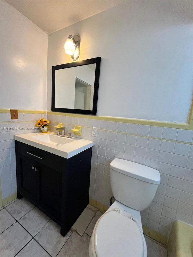 bathroom featuring tile patterned floors, a wainscoted wall, toilet, tile walls, and vanity