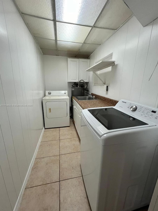 laundry area featuring baseboards, washer and clothes dryer, light tile patterned flooring, cabinet space, and a sink