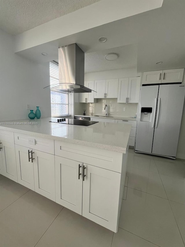 kitchen featuring light tile patterned floors, white refrigerator with ice dispenser, island range hood, white cabinets, and black electric cooktop