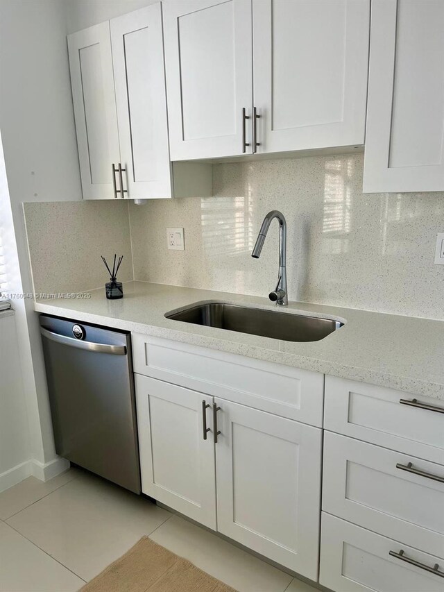 kitchen with a sink, backsplash, dishwasher, and white cabinetry