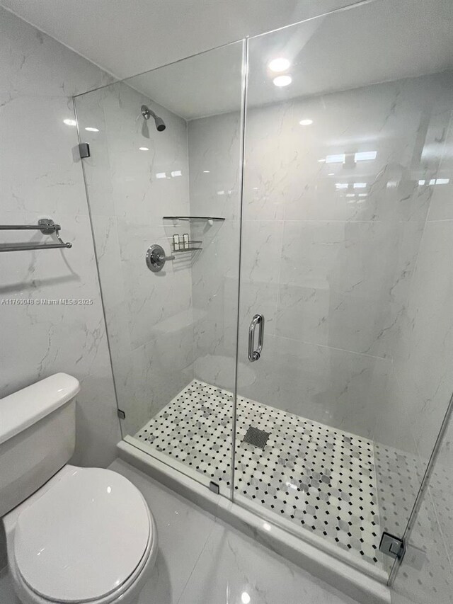 bathroom featuring a marble finish shower and toilet