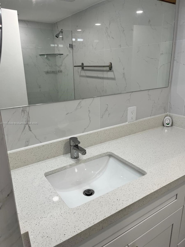 full bathroom with a marble finish shower and vanity