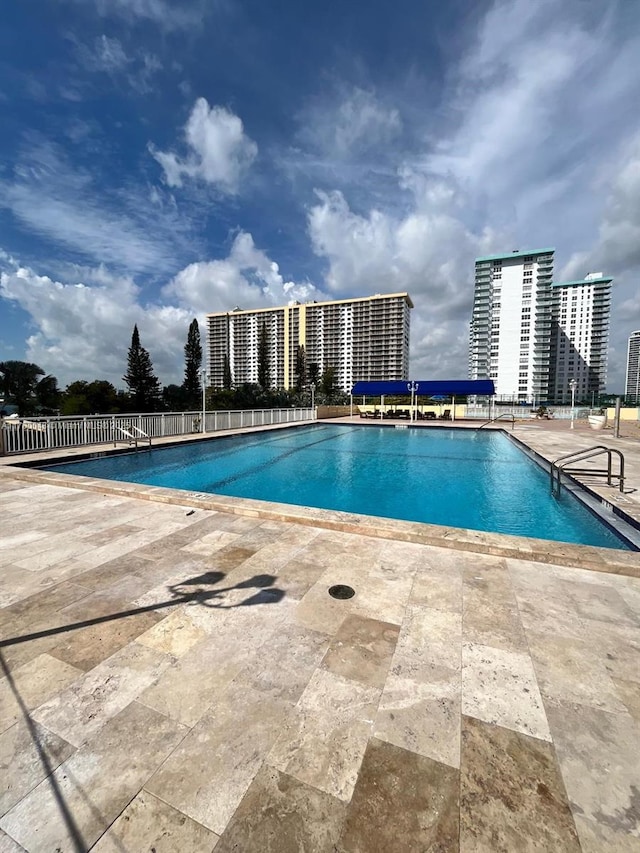 pool with a patio area and a city view