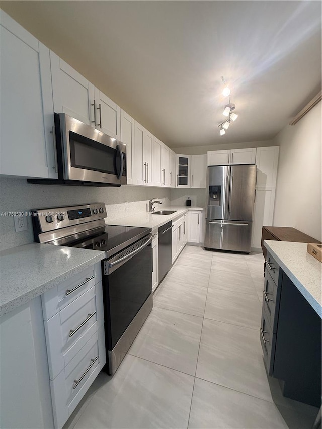 kitchen featuring a sink, stainless steel appliances, light stone countertops, and white cabinets