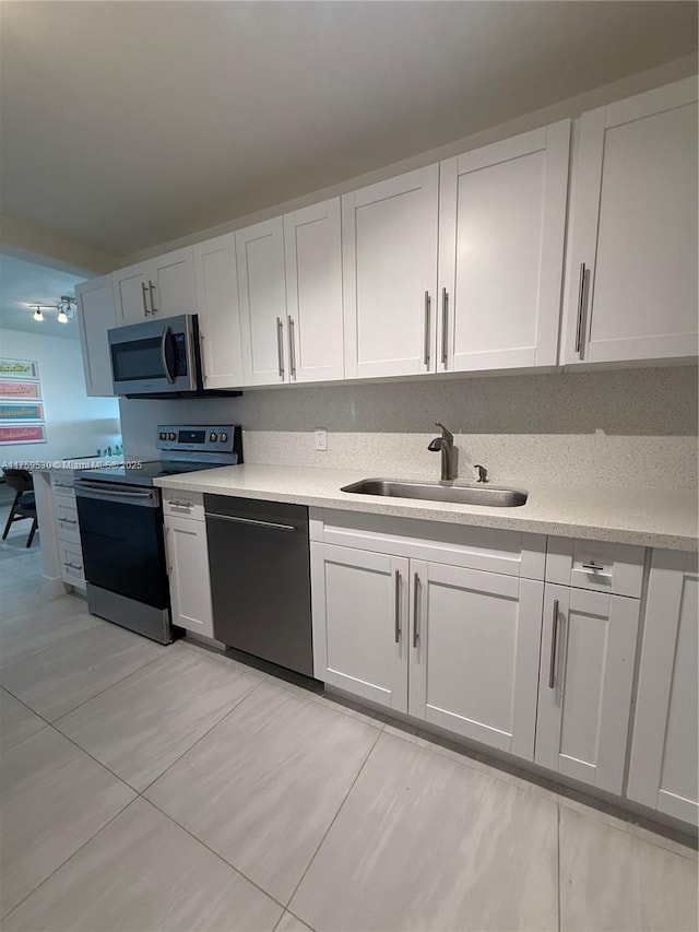 kitchen featuring a sink, appliances with stainless steel finishes, white cabinets, and light countertops