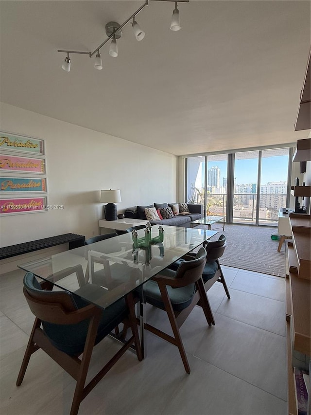 dining room featuring rail lighting, a view of city, and floor to ceiling windows