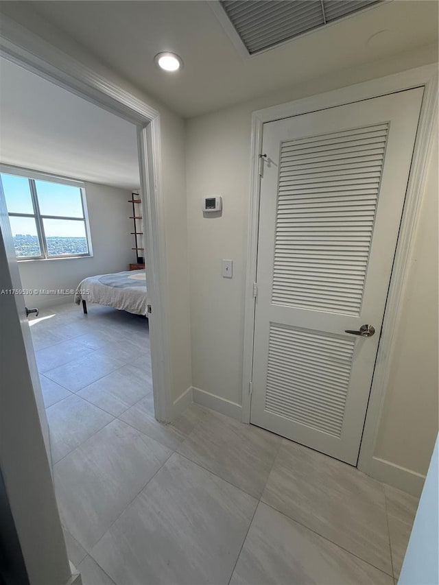 corridor with light tile patterned floors, visible vents, and baseboards