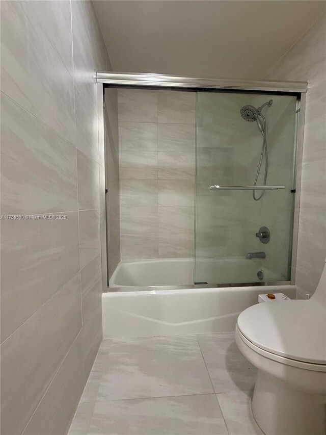 full bathroom with toilet and bath / shower combo with glass door