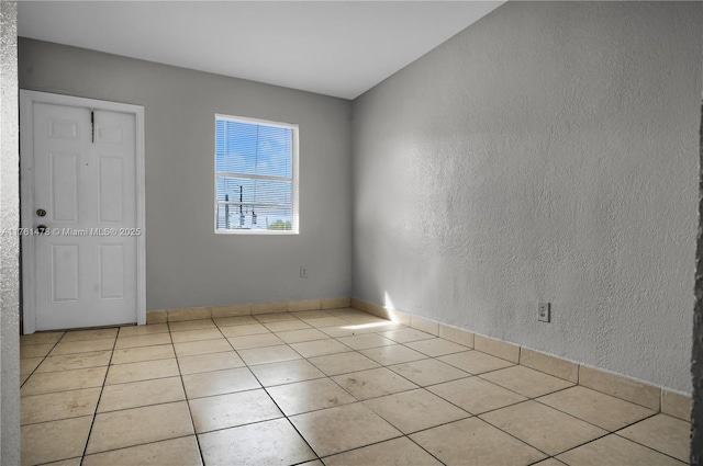 tiled empty room featuring a textured wall