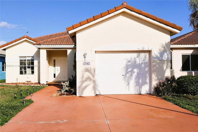 mediterranean / spanish-style house with stucco siding, driveway, a tile roof, and a garage