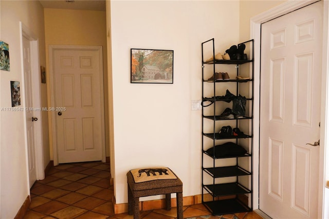 hallway with baseboards and dark tile patterned floors