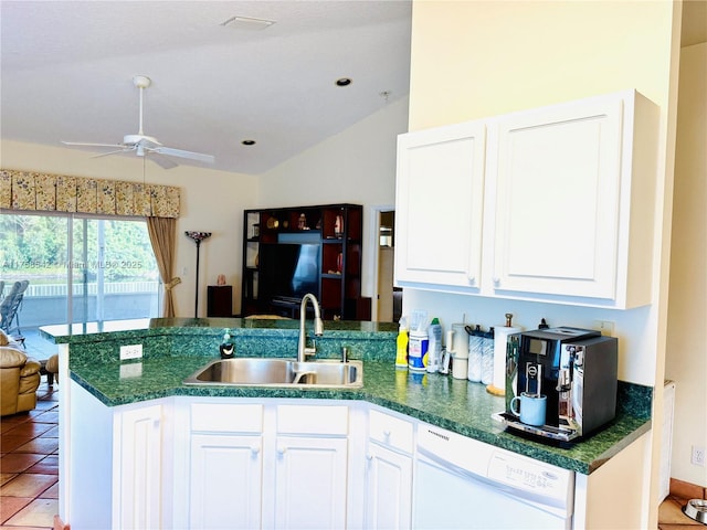 kitchen featuring a peninsula, a sink, vaulted ceiling, dishwasher, and dark countertops