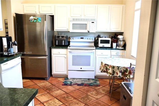 kitchen with white appliances, dark countertops, and white cabinetry