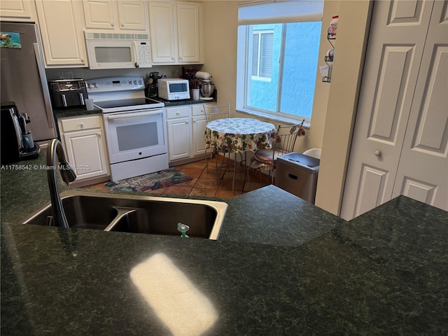 kitchen featuring white cabinets, white appliances, and a sink