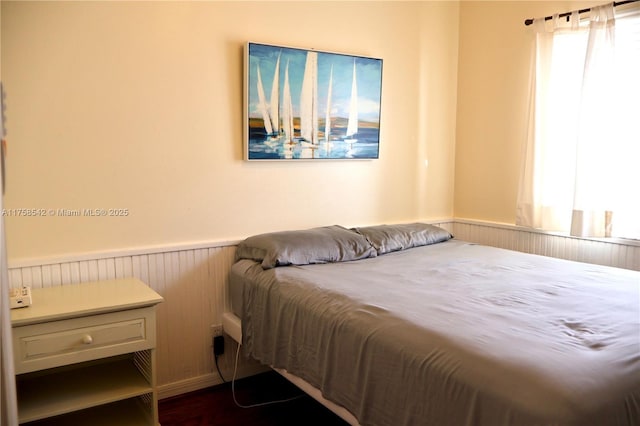 bedroom with multiple windows and a wainscoted wall