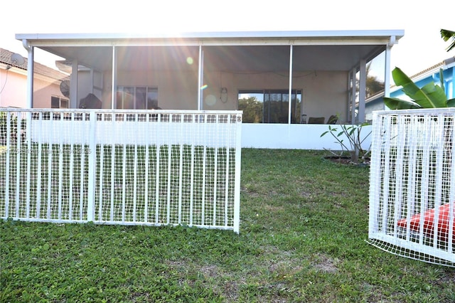 exterior space with a lawn, a sunroom, and stucco siding