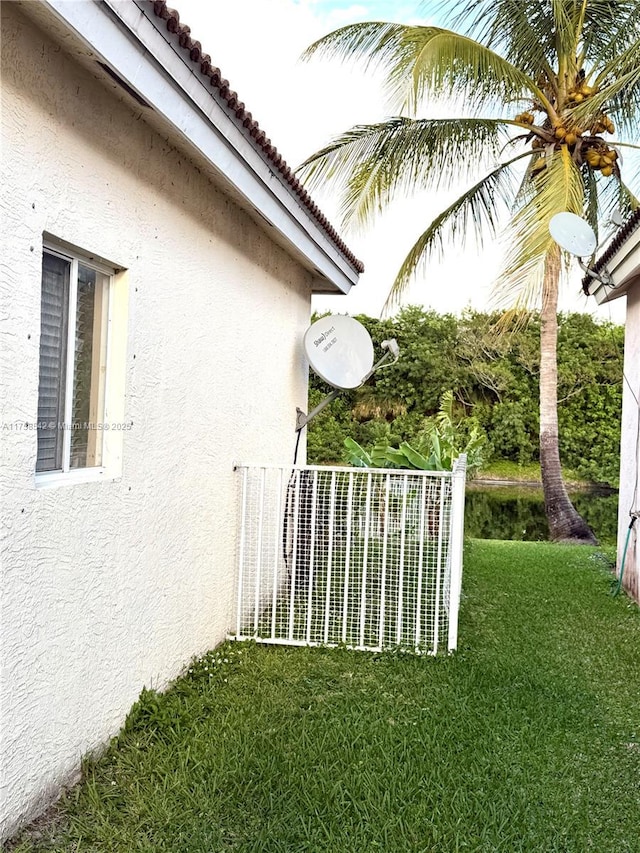 view of side of property featuring stucco siding, a tiled roof, and a lawn