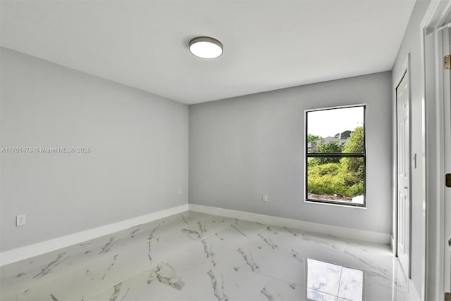 spare room with baseboards and marble finish floor