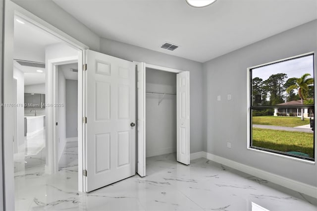 unfurnished bedroom featuring visible vents, marble finish floor, ensuite bathroom, a closet, and baseboards