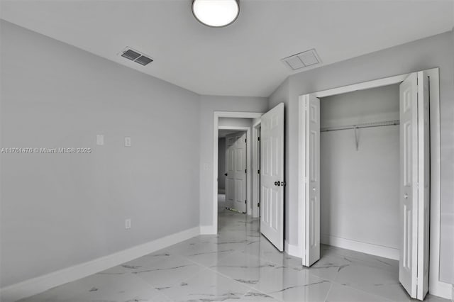 unfurnished bedroom with a closet, visible vents, marble finish floor, and baseboards