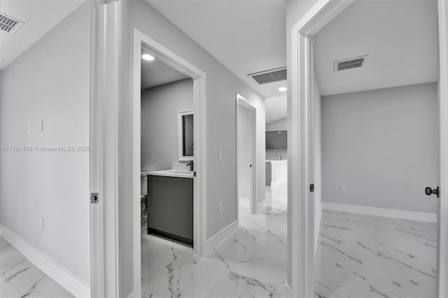 corridor featuring visible vents, baseboards, and marble finish floor