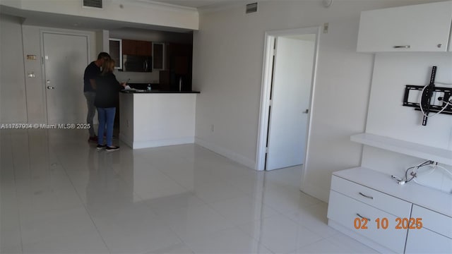 kitchen with white cabinets, baseboards, and visible vents