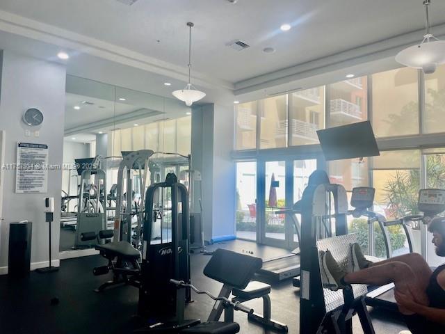 gym with a high ceiling, baseboards, visible vents, and expansive windows