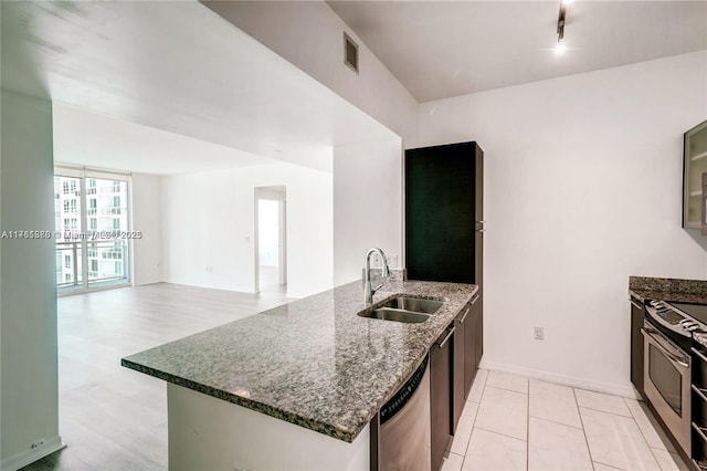 kitchen with dark stone countertops, visible vents, a peninsula, stainless steel appliances, and a sink