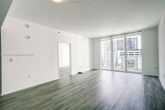 empty room with a wall of windows, baseboards, and wood finished floors