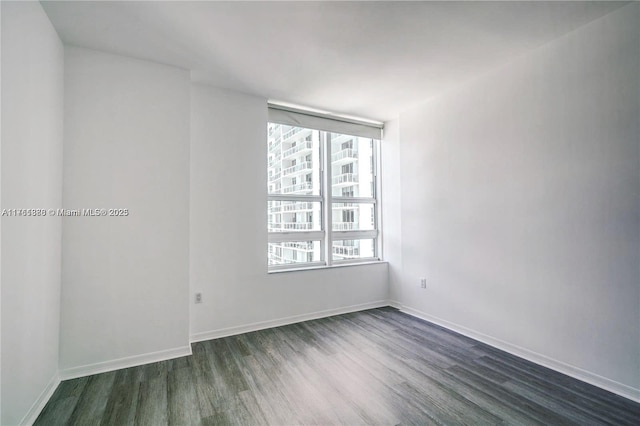 spare room featuring baseboards and dark wood-style flooring