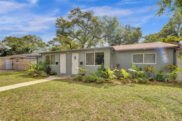 single story home with stucco siding, a front yard, and fence