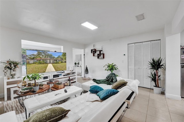 living room featuring light tile patterned flooring, visible vents, and baseboards