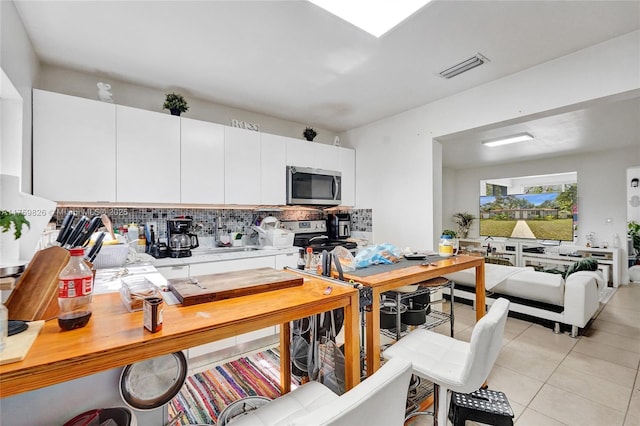 kitchen featuring tasteful backsplash, visible vents, light tile patterned floors, appliances with stainless steel finishes, and white cabinetry