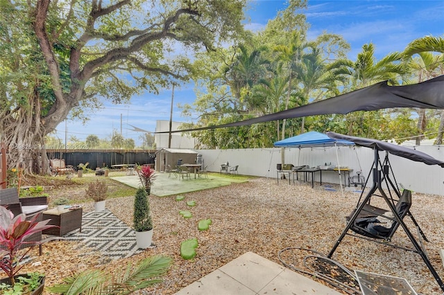 view of yard with a storage shed, a patio, a fenced backyard, and an outbuilding