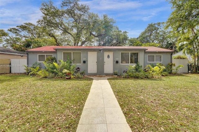 ranch-style house with stucco siding, a front lawn, and fence