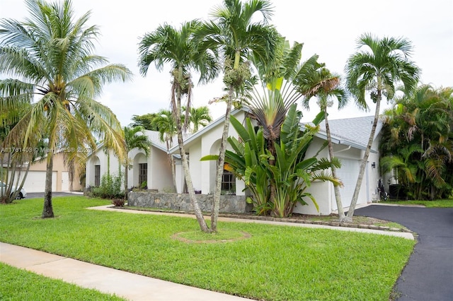 view of front of home with stucco siding, an attached garage, driveway, and a front lawn