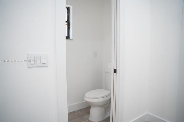 bathroom featuring toilet, baseboards, and wood tiled floor