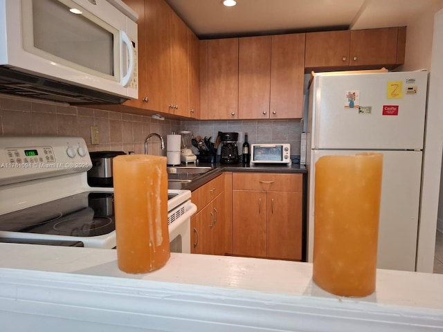 kitchen with a toaster, decorative backsplash, brown cabinets, white appliances, and a sink