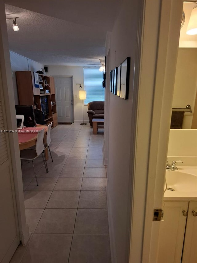 corridor featuring a sink, a textured ceiling, and tile patterned floors