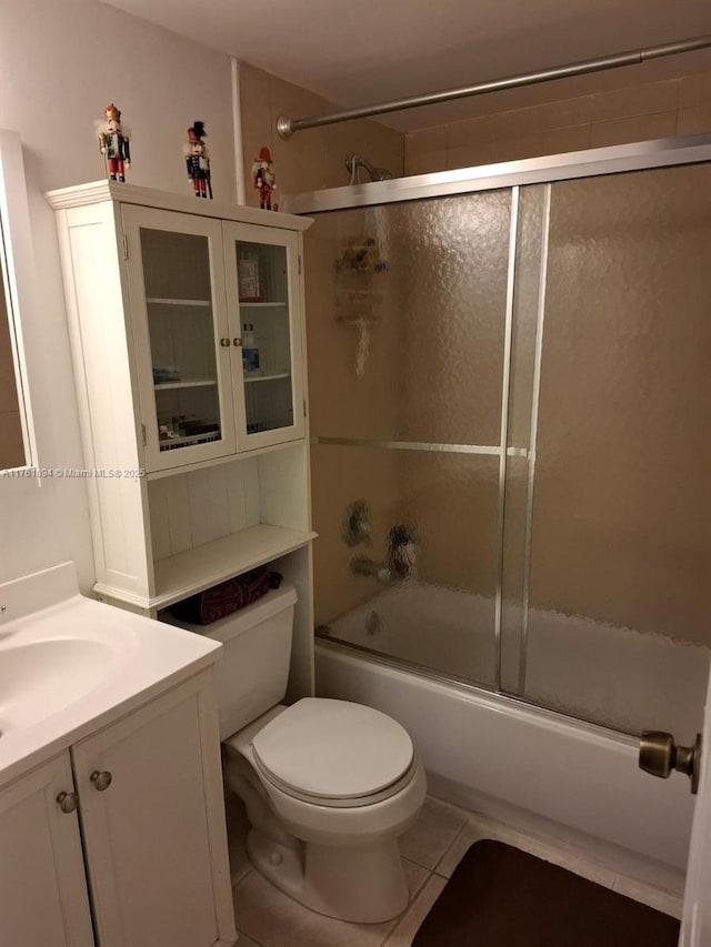 bathroom featuring tile patterned flooring, toilet, vanity, and bath / shower combo with glass door