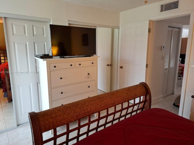 bedroom with light tile patterned floors, visible vents, and a textured ceiling