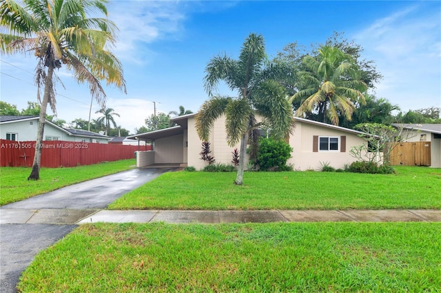 view of front of house featuring an attached carport, a front yard, fence, stucco siding, and aphalt driveway