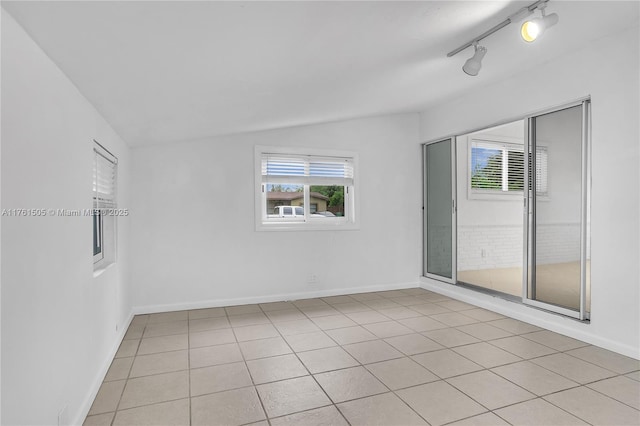 spare room featuring a wealth of natural light, baseboards, and vaulted ceiling